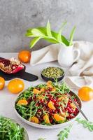 klaar naar eten fruit salade van granaatappel, mandarijn, rucola en pompoen zaden in een bord Aan de tafel. biologisch vegetarisch voedsel. foto