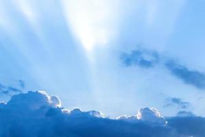 de zonnestraal achter de wolken in de blauwe lucht foto