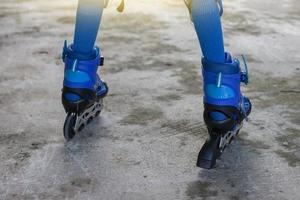 weinig jongen aan het leren rol vleet door vervelend blauw rol vleet schoenen Aan cement vloer. foto