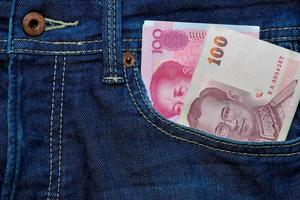 yuan of rmb en Thais baht in jeans zak- foto