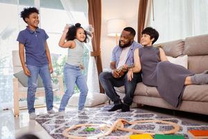 gelukkig Afrikaanse Amerikaans familie, zoon, dochter, ouders dansen samen in leven kamer foto