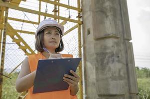 een Aziatisch vrouw ingenieur werken Bij een snelweg brug bouw website, civiel arbeider inspecteren werk Aan kruispunt bouw foto