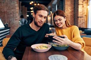 schattig mannen en Dames in een restaurant met een telefoon in hun handen selfie foto