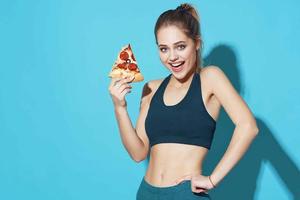 vrouw in sport- uniform aan het eten pizza voedsel eetpatroon blauw achtergrond foto