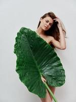 vrouw met naakt lichaam verbergt achter een palm blad exotisch studio foto