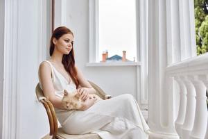 mooi vrouw strelen een kat zittend in een stoel buitenshuis dieren foto