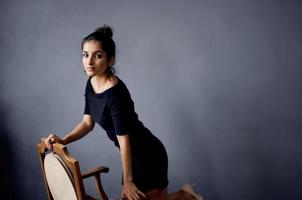 mooi vrouw oorbellen sieraden poseren in de buurt de stoel zwart jurk levensstijl studio foto