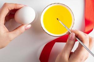 vrouw schildert op witte eieren voor Pasen foto