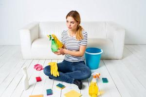 vrouw zittend Aan de verdieping met schoonmaak benodigdheden schoonmaak onderhoud huiswerk foto