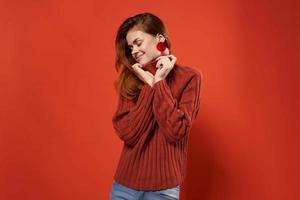 vrolijk vrouw in een rood trui bedenken oorbellen mode studio foto