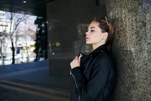 vrouw in leer jasje Aan de straat in de stad en editie zonnebril in de achtergrond foto