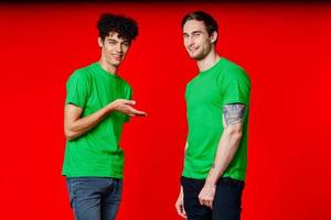 twee vrienden in groen t-shirts pret communicatie rood achtergrond foto