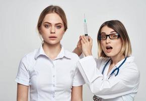 een verpleegster in een medisch japon houdt een injectiespuit in haar hand- en een geduldig Aan een licht achtergrond foto