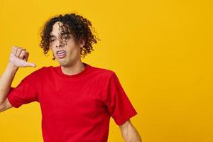 ontevreden grappig Kaukasisch jong Mens in rood t-shirt tonen dis Leuk vinden gebaar poseren geïsoleerd Aan geel studio achtergrond. de het beste aanbod met vrij plaats voor reclame. emoties voor elke dag concept foto