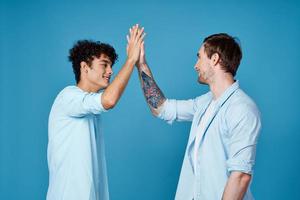 jong jongens in bij elkaar passen t-shirts en overhemden pret groeten blauw achtergrond vrienden foto