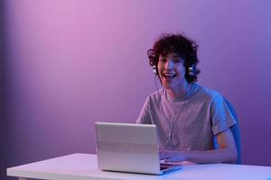 gekruld vent cyberspace spelen met hoofdtelefoons in voorkant van een laptop geïsoleerd achtergrond foto