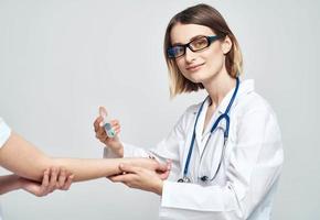 een vrouw dokter in een medisch japon is geven een injectie naar een geduldig foto
