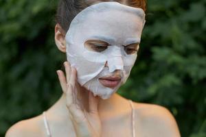 mooi vrouw gezicht masker tintje uw gezicht met uw hand- schoonheidsspecialiste bladeren in de achtergrond foto