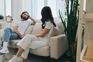 Mens en vrouw vrienden zittend Aan de bankstel en glimlachen vrolijk pratend naar elk andere hebben een mooi zo tijd samen. levensstijl in geluk Bij huis foto