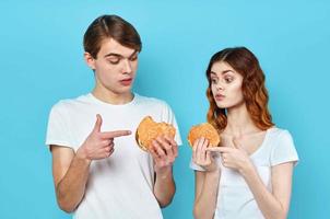 Mens en vrouw in t-shirts met hamburgers in de handen van snel voedsel eetpatroon foto