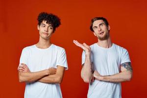 twee vrienden in wit t-shirts bouw teams hij emoties rood achtergrond foto