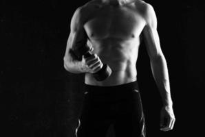 sportief Mens met halters in handen pompen omhoog spieren opdrachten donker achtergrond foto