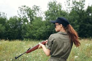 leger vrouw Holding een geweer jacht- levensstijl groen bladeren foto