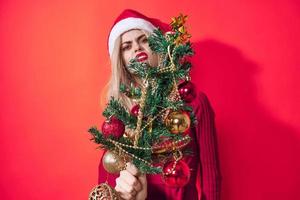 mooi vrouw Holding Kerstmis boom decoratie vakantie pret rood achtergrond foto