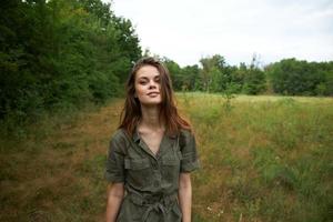 vrouw Aan natuur in een groen overall, een glimlach looks vooruit naar de natuur foto