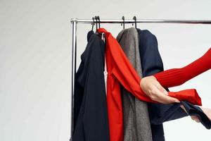 mooi vrouw in een rood jasje in de buurt de garderobe kleinhandel licht achtergrond foto