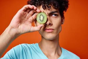 vent in blauw t-shirt kiwi Holding fruit studio rood achtergrond foto