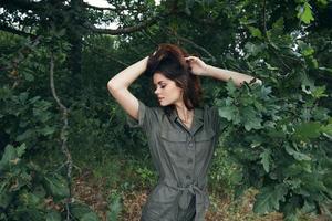 vrouw in de Woud een groen jumpsuit looks naar groen bladeren achtergrond natuur foto