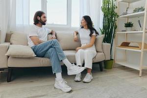 mannetje en vrouw Aziatisch vrienden zittend Aan de bankstel en hebben pret pratend naar elk andere met een glimlach hebben een mooi zo tijd samen. levensstijl in geluk Bij huis foto