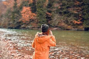 vrolijk vrouw toerist in een jasje herfst Woud rivier- natuur foto