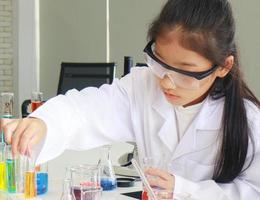 jonge vrouwelijke student doet wetenschappelijke experimenten met een chemische buis in een laboratorium
