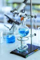 chemisch glaswerk met blauw vloeistoffen Aan tafel in laboratorium foto