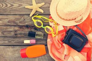 zomer vrouwen strand accessoires voor uw zee vakantie Aan de oud houten achtergrond. afgezwakt afbeelding. foto