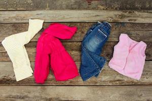 kinderen kleding en accessoires jeans, jasje, haar- clips en warm hesje Aan oud houten achtergrond. top visie. foto