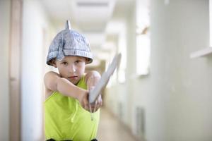 een kind is spelen strijder. grappig jongen in een helm met een zwaard. foto