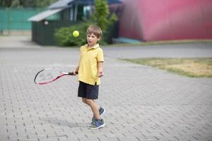 kind met een tennis racket en een bal. jongen tennis speler. schooljongen gaat in voor sport- foto