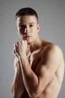 portret van een vent Aan een grijs achtergrond naakt arm spieren bodybuilder foto
