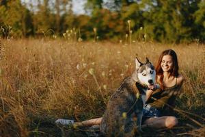 vrouw zittend in veld- met teckel hond glimlachen terwijl uitgeven tijd buitenshuis met hond vriend foto