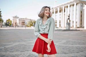 vrolijk vrouw in rood rok in de plein buitenshuis poseren foto