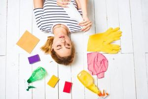 vrouw in gestreept t-shirt leugens Aan de verdieping schoonmaak benodigdheden wasmiddel huiswerk foto