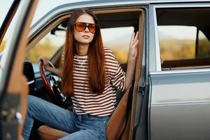 een vrouw bestuurder in zonnebril gestopt de auto Aan de weg in een pktkshestvie en is resting op zoek Bij een mooi visie foto