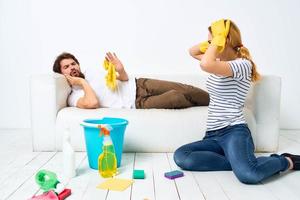 een Mens leugens Aan een bank. een vrouw reinigt omhoog huishouden schoonmaak foto