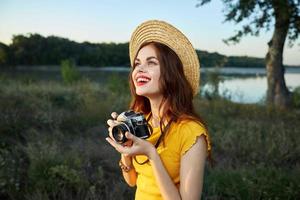 vrouw in natuur fotograaf camera in handen glimlach kijken omhoog hoed foto