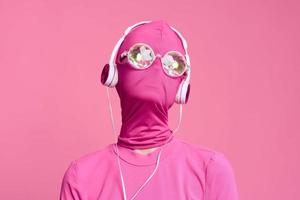 vrouw kunst beats conceptuele portret Aan helder roze was- vervelend glimmend neon bril, roze masker en hoofdtelefoons foto