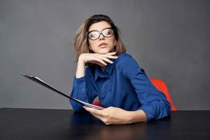 vrouw in een blauw overhemd zit Bij de tafel map in handen kopiëren ruimte foto