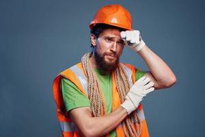 Mens in oranje verf handschoen professioneel bouw blauw achtergrond foto